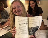 two girls sitting on a bed holding a book